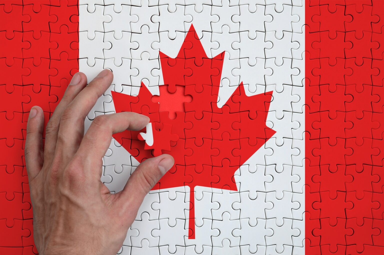 Canada flag is depicted on a puzzle, which the man's hand completes to fold.
